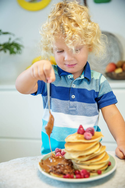 Little curly boy eating sweet pancakes - 写真・画像