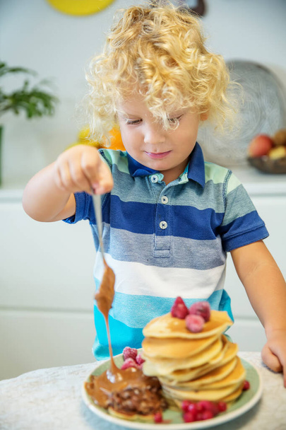 Little curly boy eating sweet pancakes - 写真・画像