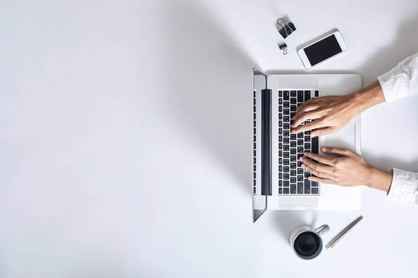 A man is typing on laptop keyboard on modern white office desk,  - Фото, изображение