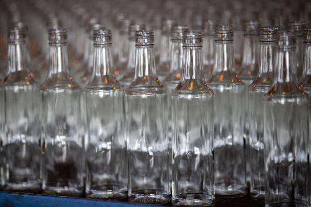Glaswerk. Glasindustrie. Veel glazen flessen op een fabrieksband. - Foto, afbeelding