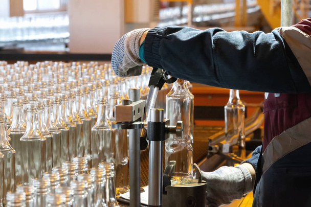 Glashütten. Glasindustrie. arbeitende Hände halten eine Glasflasche auf dem Hintergrund eines Förderbands. - Foto, Bild