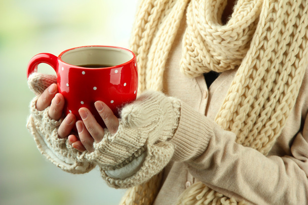 Female hands with hot drink, on light background - Foto, Imagen