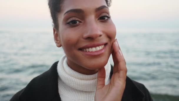 Close up tiro de bela flerte menina afro-americana feliz olhando na câmera posando junto ao mar
  - Filmagem, Vídeo