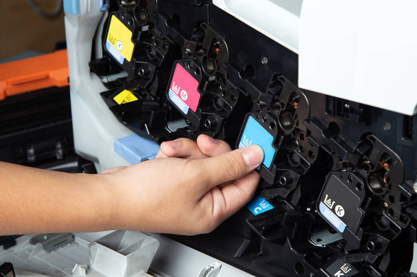 Hombre de negocios o técnico está empujando o tirando de los cartuchos del equipo de impresión tono de la impresora multifunción láser jet en la oficina. Primer plano de los cartuchos de tinta CMYK para impresora láser
. - Foto, imagen