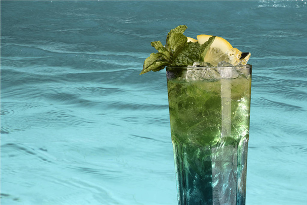 Erfrischendes alkoholisches Getränk im Glasbecher am Rande des Schwimmbeckens - Foto, Bild