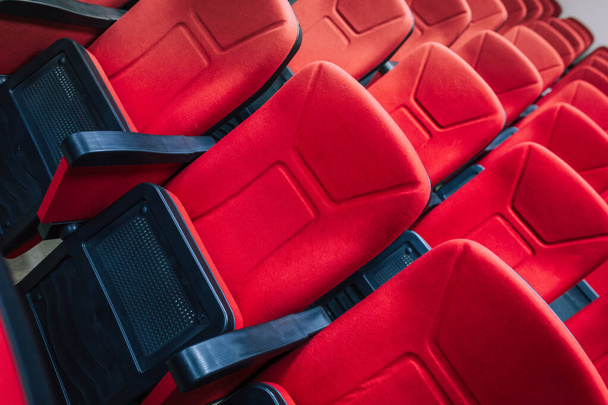 Red cineme καρέκλες ή πολυθρόνες στο θέατρο. Κόκκινες καρέκλες σε αίθουσα συνεδρίων ή σεμιναρίων. - Φωτογραφία, εικόνα