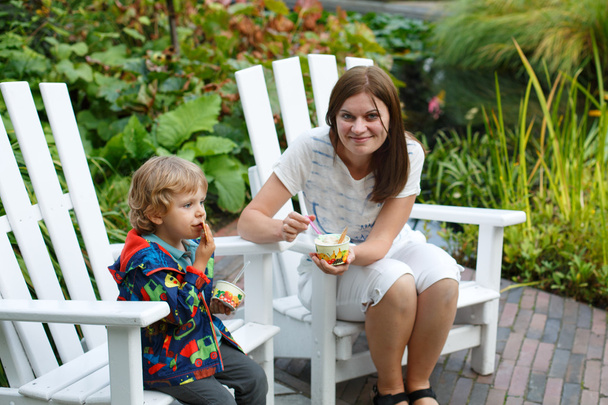 Jovem mulher e menino pequeno comendo sorvete ao ar livre
 - Foto, Imagem