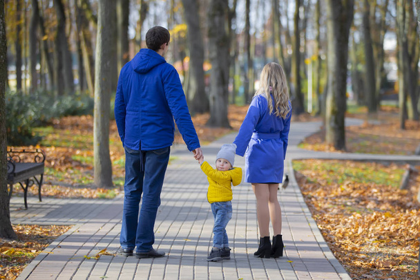 Rodzina na spacerze. Matka ojciec i mały syn spacerują w jesiennym parku. - Zdjęcie, obraz