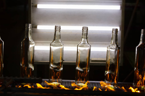 コンベアベルトのガラス瓶を火にかける。瓶製造工程 - 写真・画像