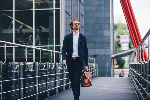 Atractivo hombre de negocios con gafas y un traje de oficina salió a trabajar en la calle
 - Foto, imagen