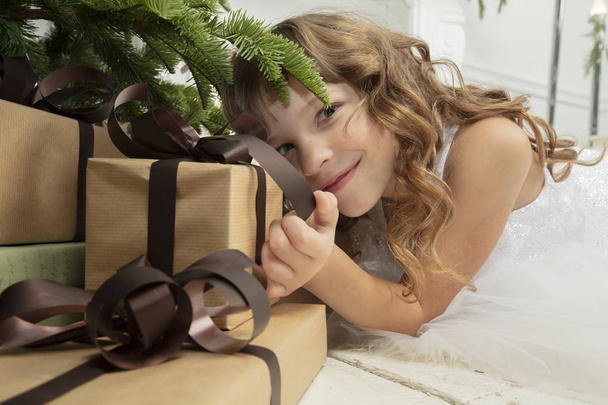 Bambino divertente a Natale. Ragazza sotto l'albero di Natale con regali
. - Foto, immagini
