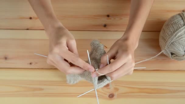 dziewczęce ręce na drutach na drewnianym tle stołu - Materiał filmowy, wideo