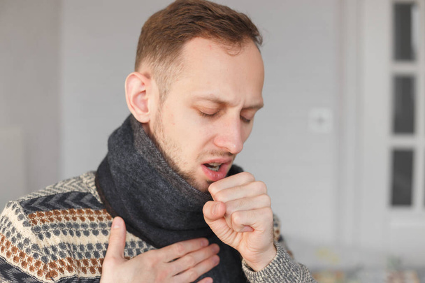 Jeune homme avec une écharpe sur le cou tousse à cause du froid et du mal de gorge
 - Photo, image