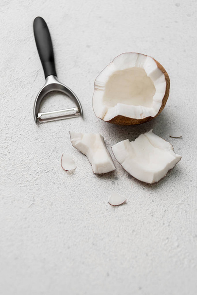 noix de coco avec un couteau pour légumes sur fond clair
 - Photo, image