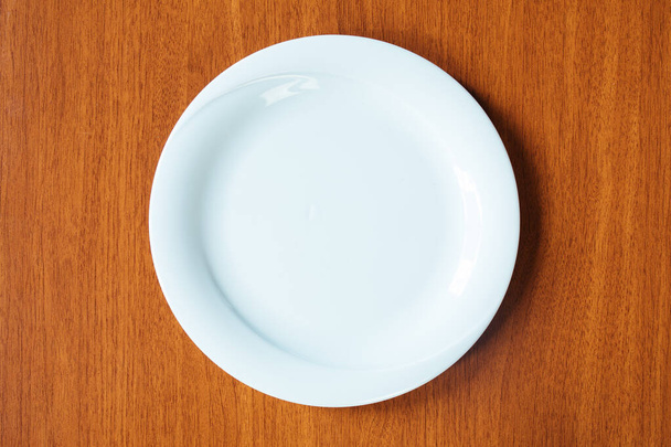 Pusty biały talerz na drewnianym stole od góry widok - Zdjęcie, obraz
