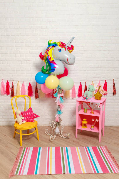 Balloons in the form of a unicorn. Idea for decorating unicorn style first year birthday party. Paper garlands on a white brick wall and photo booth props. Unicorn decoration for festival party for girl. - Фото, изображение