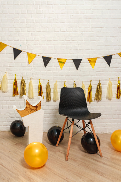 Gold black paper garlands on a white brick wall.  Matte and glossy golden black style idea for decorating first year birthday party. Golden is the first year of life the number one crown photo booth - Photo, Image