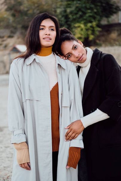 Beautiful stylish African American and Asian girls dreamily posing together on beach - Fotografie, Obrázek
