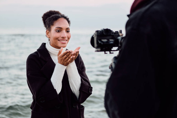 美しいかわいいですアフリカ系アメリカ人の女の子喜んで海によって写真セッション中にカメラにエアキスを送信 - 写真・画像