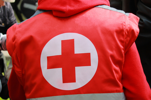 Medical staff in uniform with a red cross provides medical care at a mass event. Nurse helps injured people on city street - 写真・画像