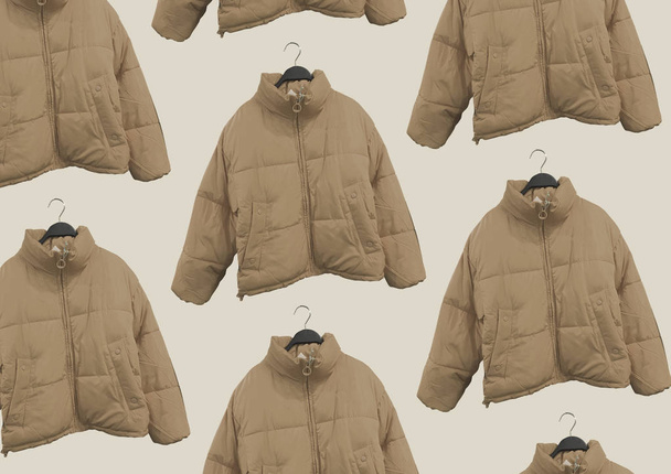 Mulheres castanhas moda jaqueta padrão. Uma seleção de jaquetas diferentes em cabides isolados em fundo bege. Padrão de roupas de inverno. Composição de roupas. Deitado. Casaco acolchoado
 - Foto, Imagem