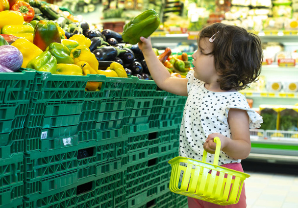Child shopping peppers in supermarket. Concept for buying fruits - Фото, зображення