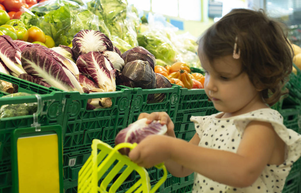 Child shopping radicchio in supermarket. - Photo, Image