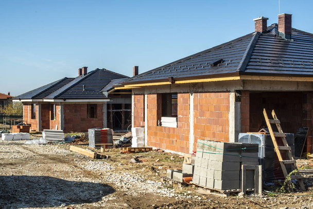 Bouwen van een nieuw stenen huis met zwart dak. Kleine huizen op nadelen - Foto, afbeelding