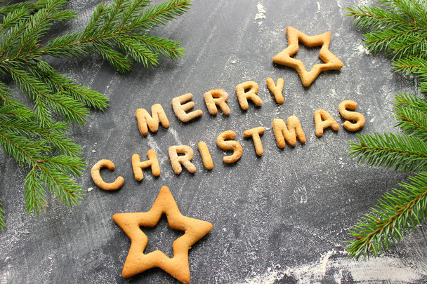 Baked letters Merry Christmas, stars, snowflakes.Greeting card with gingerbread. Christmas card made of gingerbread on a wooden table. Text merry Christmas from ginger cookies on a baking sheet - Foto, Bild