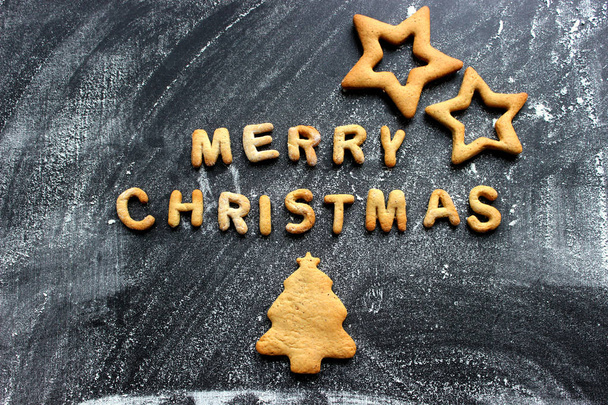 Baked letters Merry Christmas, stars, snowflakes.Greeting card with gingerbread. Christmas card made of gingerbread on a wooden table. Text merry Christmas from ginger cookies on a baking sheet - Valokuva, kuva