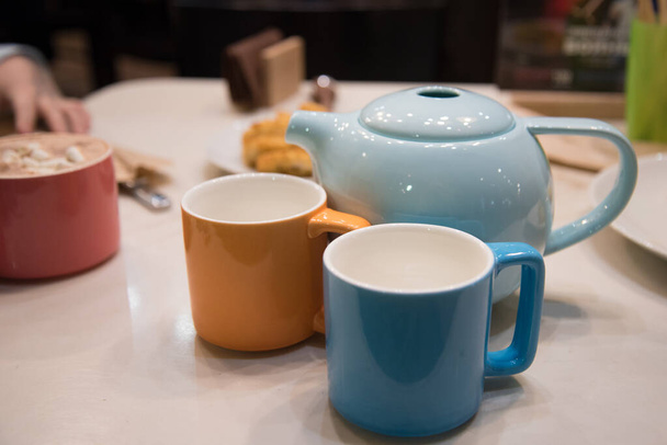 Life style. The cozy atmosphere in the cafe. On the table is a colored teapot and mugs. - Foto, imagen