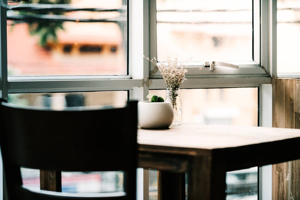 明るい窓の横にはコーヒーテーブルがあり、ゆったりとした落ち着いた雰囲気の中でコーヒーや食べ物を楽しむことができます。 - 写真・画像