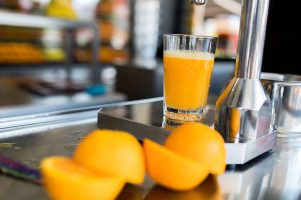 Exprimir naranja con exprimidor de cítricos de mano cromado. Jugo de naranja. Multivitamínico, vitamina C
 - Foto, imagen