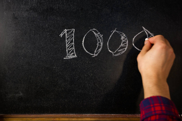 Hand writes the number 1000 of subscribers on the board. - Photo, Image
