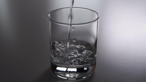 Pure sparkling water pours a glass on a gray table. Eating Eco Products for Diet and Weight Loss - Imágenes, Vídeo