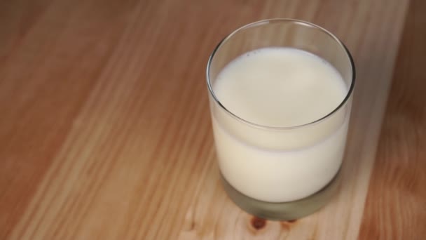Runde Haferkekse fallen auf einen Holztisch neben einem Glas Milch. Zeitlupe. gesundes Frühstück mit pflanzlichen Produkten - Filmmaterial, Video