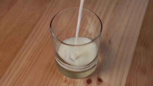 Oat milk fills a glass on a wooden table. The use of vegetable milk for breakfast - Filmagem, Vídeo