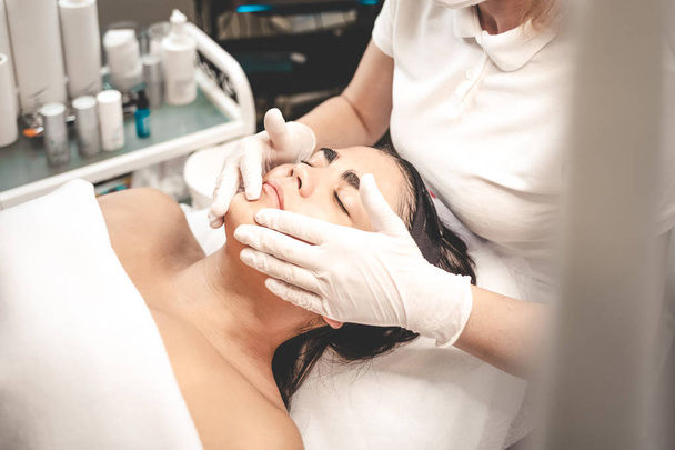 Cosmetologist mancha a cara do paciente com a nata nutritiva. Massagem facial
 - Foto, Imagem