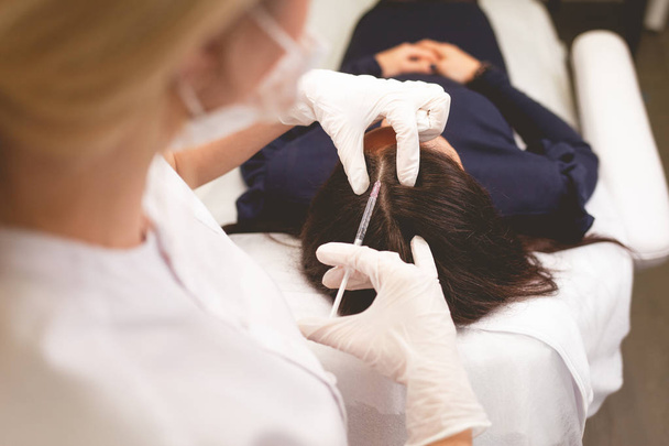 Girl has hair problems. Mesotherapy procedure. Doctor makes an injection against hair loss. - Foto, imagen