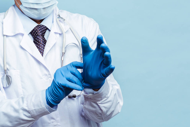 médecin met des gants en caoutchouc, des soins de santé et des médicaments. Isoler sur fond bleu
 - Photo, image