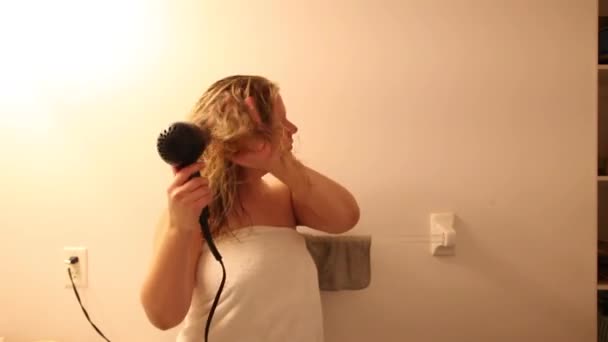 Frau mit langen blonden Haaren trocknet ihre Haare mit einem heißen Trockner  - Filmmaterial, Video