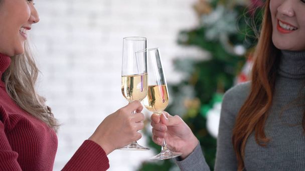 Dvě mladé ženy držící sklenice šampaňského a pronášející přípitek s úsměvem ve tváři. Koncept oslavy a pozdravu - Fotografie, Obrázek
