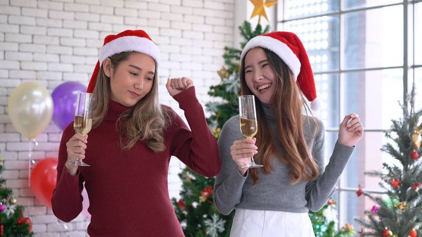 Noel partisinde dans eden ve şampanya içen Asyalı kadınlar. Noel kutlaması - Fotoğraf, Görsel