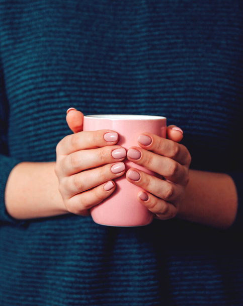 Girl with a manicure holding a pink Cup. - Φωτογραφία, εικόνα