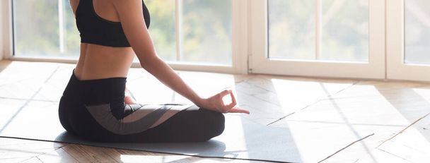 Cropped image of meditating woman sitting on yoga mat - 写真・画像