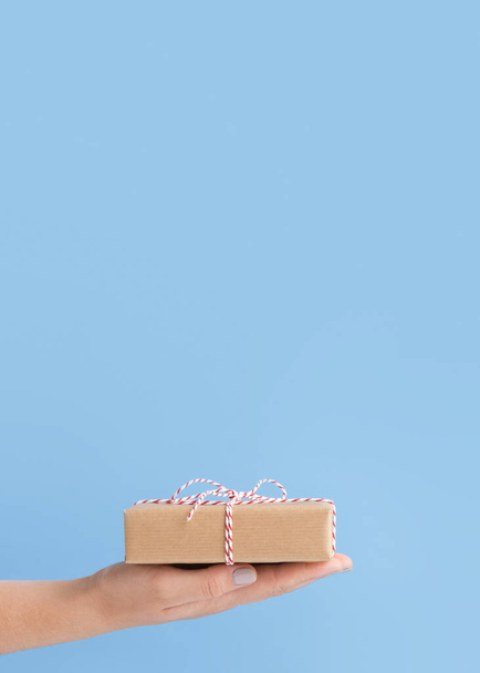Τυλιγμένο σε χαρτί Κουτί δώρου διακοπών στη γυναικεία παλάμη - Φωτογραφία, εικόνα