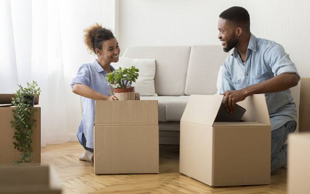 Happy Spouses Packing Stuff In Boxes Sitting On Floor Indoor - Photo, Image