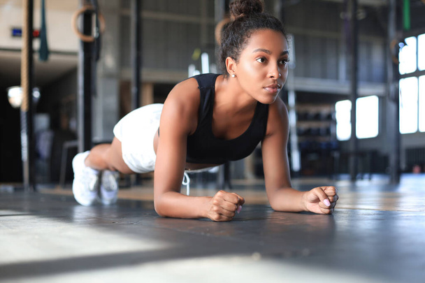 Portrait of a muscular woman on a plank position. - Фото, зображення