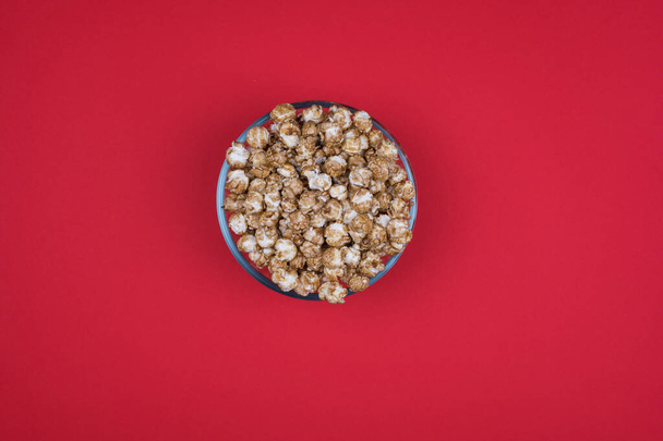 Caramel sweet popcorn in glass bowl isolated on red background top view. Top view, copy space. - Foto, Imagem