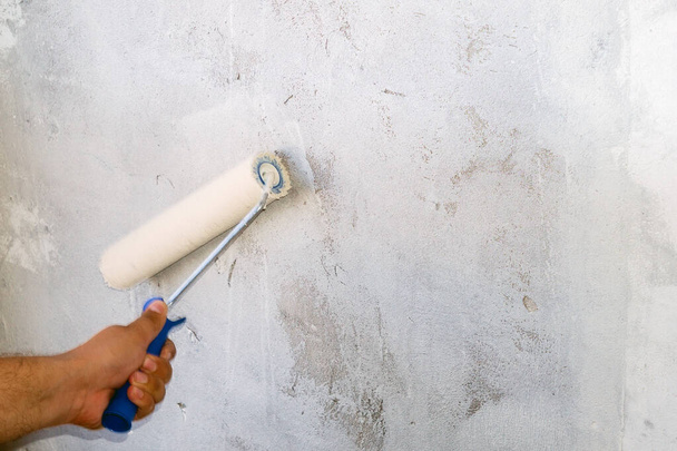 egy régi betonfalat fest egy görgővel. - Fotó, kép